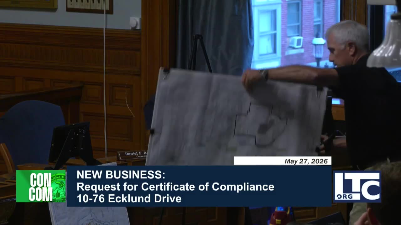 Architectural site plan displayed on easel during meeting